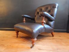 Howard Style armchair. Coveted in black leather. Turned walnut front legs, all on castors.