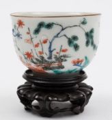 A Japanese Kakiemon teabowl: painted with a pine tree, a banded hedge, floral sprays and foliage,