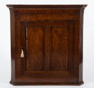 An 18th Century oak hanging corner cupboard: with a moulded cornice and canted angles,