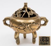 A Chinese bronze tripod incense burner and cover: decorated overall with prunus blossom,