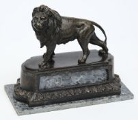 A 20th century bronze lion: raised on a shaped marble base, unsigned, 27cm. long.