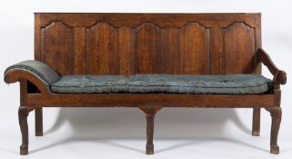 An 18th Century oak settle:, the rectangular back with five shaped and fielded panels,