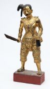 A South East Asian carved and gilded wood figure of a warrior: in traditional costume,