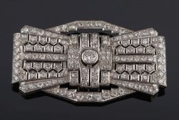 A French Art Deco diamond mounted rectangular plaque brooch: of pierced stylised ribbon bow design