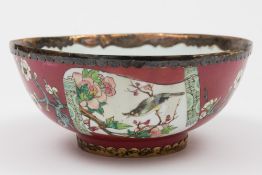 A Chinese ruby ground famille rose bowl: finely painted with scroll panels of birds amongst peony
