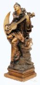 An Art Deco period painted plaster figure of Pierrot:  playing a guitar seated on a crescent moon