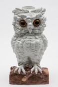 A Continental porcelain 'owl' table lamp: with inset glass eyes modelled standing on a log,