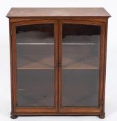An Edwardian mahogany table cabinet:, enclosed by a pair of glazed panel doors, on bun feet.