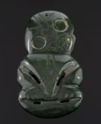 A Maori carved greenstone Hei Tiki: in orthodox stance with head tilting slightly to the right,