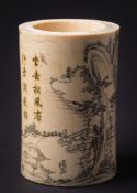 A Japanese carved ivory brush pot: decorated overall with figures in a mountainous landscape,