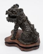 A Chinese bronze study of a temple lion: half seated with its head turned to the left,