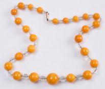 A graduated amber and glass bead single-string necklace:, the spherical amber beads between smaller,