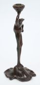 A French Art Nouveau bronzed metal novelty frog candlestick: holding a lotus pod and standing on a