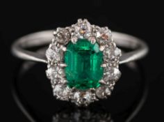 A platinum, emerald and diamond rectangular cluster ring:, the rectangular emerald 6mm x 4mm,