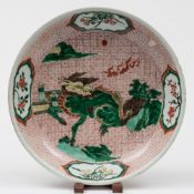A Chinese wucai dish: painted with a mythical beast by rocky outcrops and a zig-zag wall,
