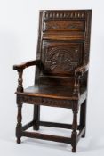 A 17th Century carved oak open armchair:, the high fielded panel back with fluted top rail,