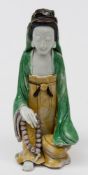 A Chinese famille verte biscuit figure of Guanyin: with dark brown hair and wearing yellow and