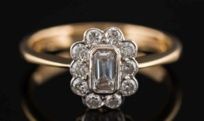 An 18ct gold and diamond oval cluster ring:, the central, baguette-cut diamond estimated to weigh 0.