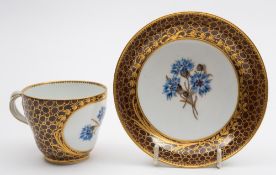 A Meissen porcelain cup and saucer: of ogee form each piece finely enamelled with a panel of three