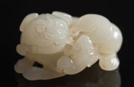 A Chinese jade carving of a reclining mythical beast: a lizard and lotus  plant to one side of its