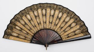A 19th century tortoiseshell and sequin decorated fan: the black silk leaf with gilt gauze and