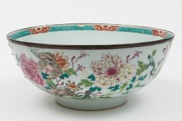 A Chinese famille rose punch bowl: painted with a butterfly, rockwork, prunus,