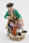 A Meissen porcelain figure group: modelled as a seated lad holding a hoop for a performing dog