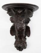 A Black Forest carved wall bracket: the semi-circular shelf mounted on a foliate backplate