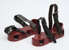 A pair of iron diving boots or exercise boots:, the red painted soles with double leather straps.