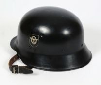 A Third Reich style model 35 steel fireman's helmet : black with eagle holding swastika badge,