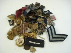 A collection of WWI & WWII cap and shoulder badges, buttons and lapel badges etc:.