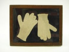 A pair of early 19th century child's silk cotton gloves mounted in a glazed frame:..