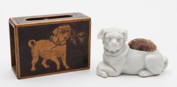 A bisque porcelain pug pin cushion and a matchbox cover: the former modelled recumbent with crossed