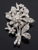 A white metal and diamond mounted floral spray brooch: with circular,