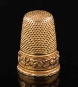 A 19th century gold thimble: with chased foliate frieze, 23mm long, apparently unmarked, 6.