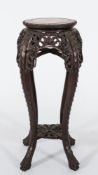 A Chinese carved hardwood circular jardiniere stand: the top inset with a panel of rouge variegated
