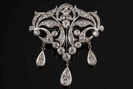 A diamond mounted pendant/brooch: of open work foliate scroll design suspending three pear shaped