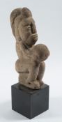 A Pre-Columbian/Mayan carved volcanic rock figure of a ball game player: seated and holding a ball