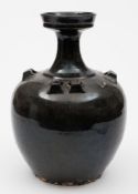 An Oriental black glazed stoneware jar: of ovoid form with waisted neck and cup-shaped rim,
