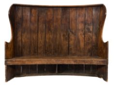 A 19th Century elm curved high back wing settle:, with plank back and concave solid seat,