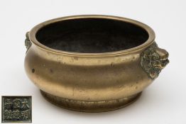 A Chinese polished bronze censer: of squat circular form, with dragon mask handles,