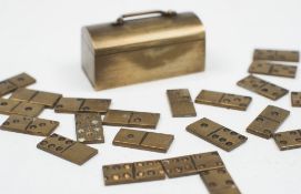 A set of novelty miniature brass travelling dominoes:, contained in a domed case, 3cm. long.