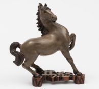 A Chinese stoneware figure of a horse: modelled in startled pose down on its rear quarters with one