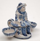 A Dutch delft figural cruet: modelled as a seated male figure flanked by panniers,
