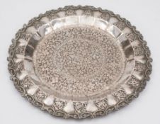 An Indian silver tray: of circular outline, decorated with scrolling foliage and flowerheads,