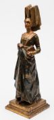 A carved wooden and polychrome decorated figure of a lady: wearing medieval costume with V-shaped