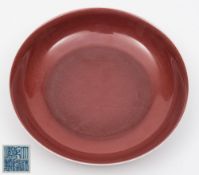 A Chinese copper-red glazed shallow dish: of circular form with rounded sides and shallow foot rim,