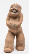 A Chinese pottery figure of a Balladeer: with smiling face and tongue extended from his open mouth