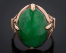 An oval jade single-stone ring: with foliate design shoulders the shank stamped '14K',