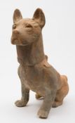 A large Chinese pottery figure of a seated dog: in alert pose with ears erect and tail coiled,